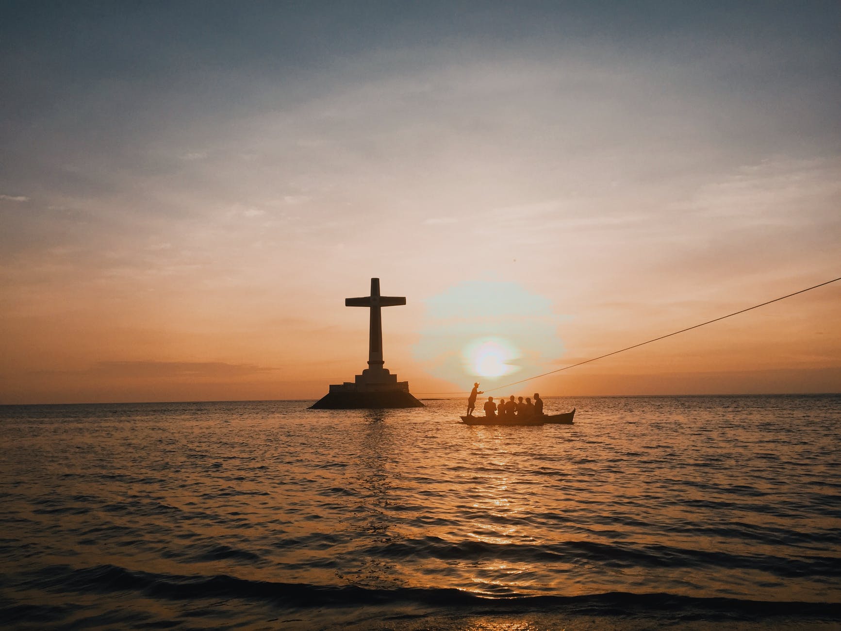 photo of cross in an ocean during dawn